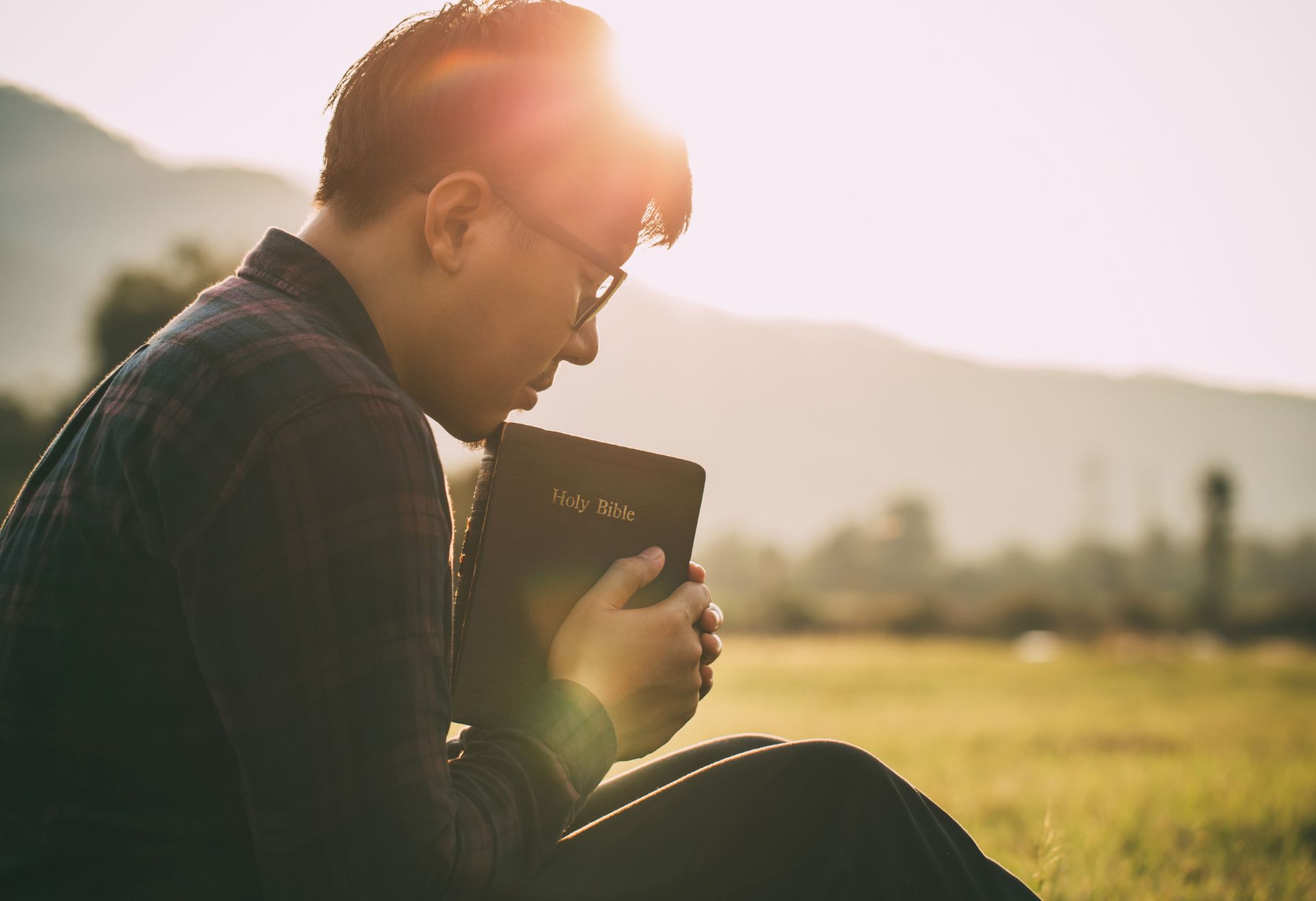 Photograph of a man holding a bible in prayer