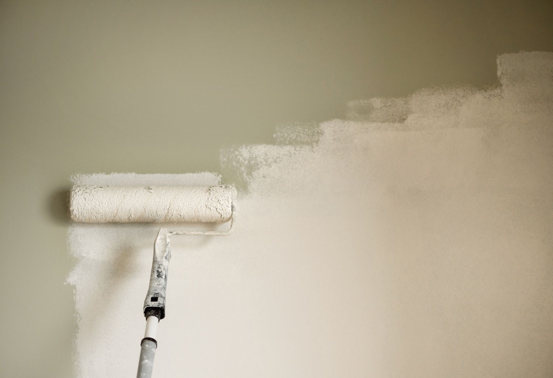 Image of a paint roller painting white onto a wall