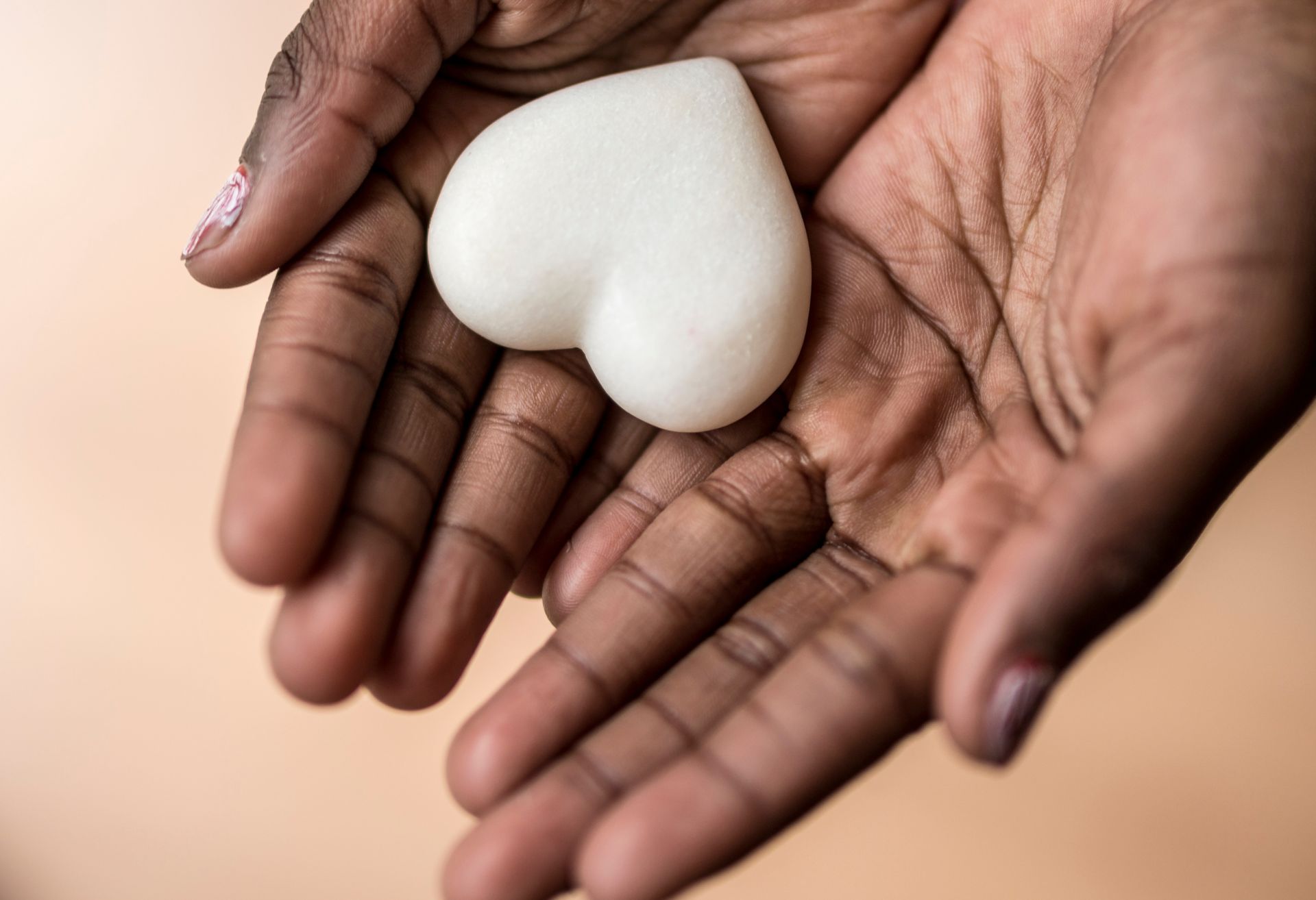 Small stone heart sitting on open hands